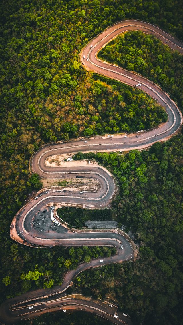 Aerial view of serpentine road through lush forest